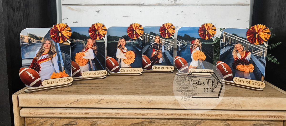 Angled close-up of personalized cheer photo plaques with school-color pom-poms